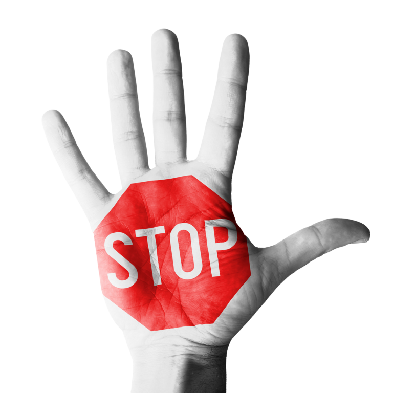 Offene Handfläche zeigt aufgedrucktes rotes Achteck mit weißer Schrift 'STOP', Hand frontal ausgerichtet mit gespreizten Fingern, vor einfarbig schwarzem Hintergrund, gut sichtbar.