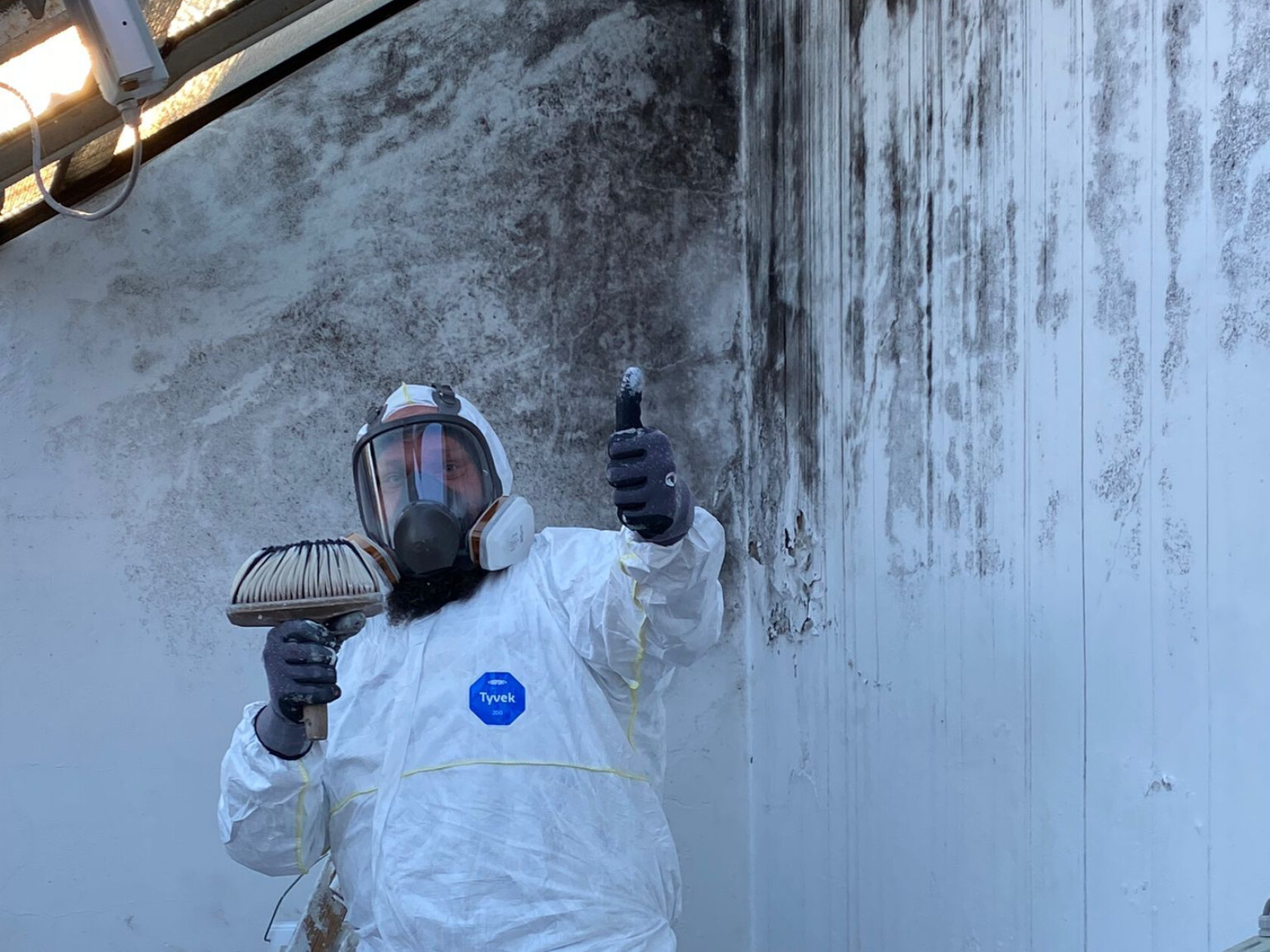 Person in weißem Schutzanzug mit Etikett 