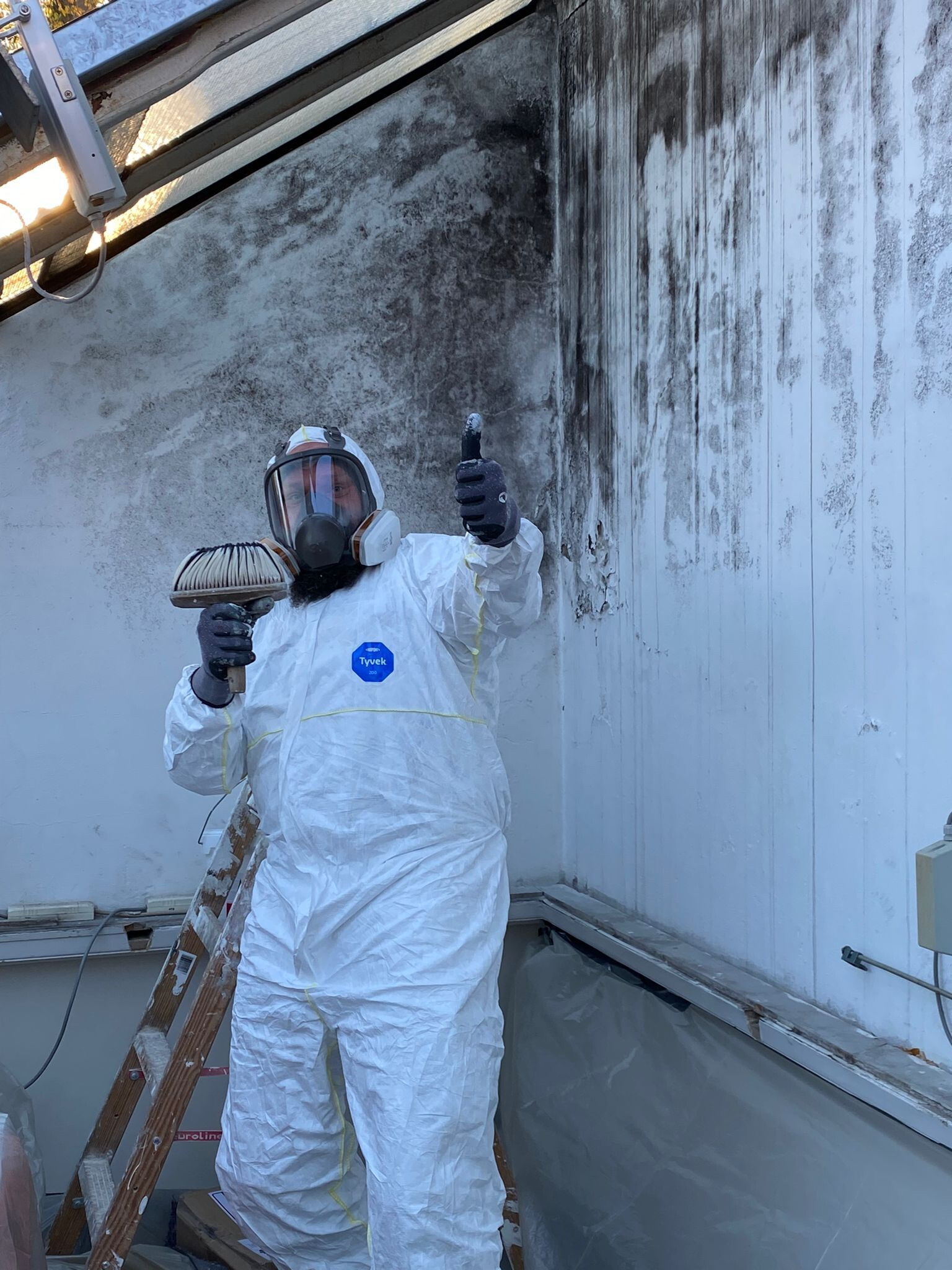 Person in weißem Schutzanzug mit Etikett 