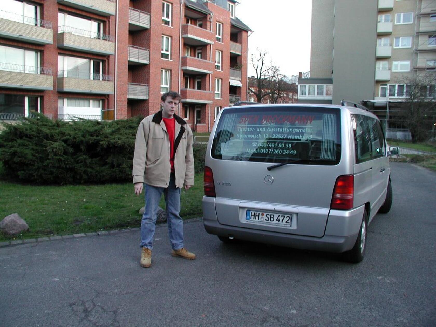 Mann steht neben silbernem Mercedes-Van (Kennzeichen 