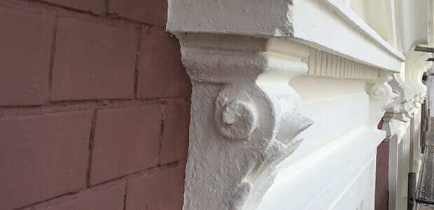 Verschnörkelter, frisch renovierter Fenstersims an ein Hausfassade
